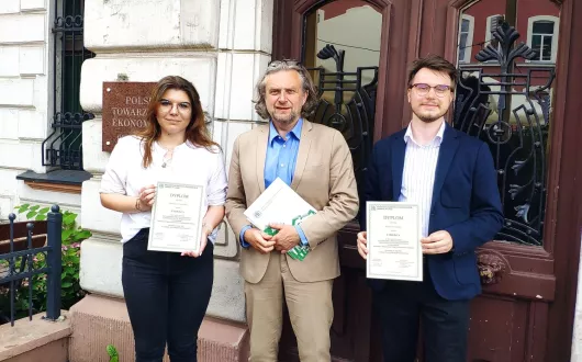 jedna kobieta i dwóch mężczyzn na tle zabytkowego budynku